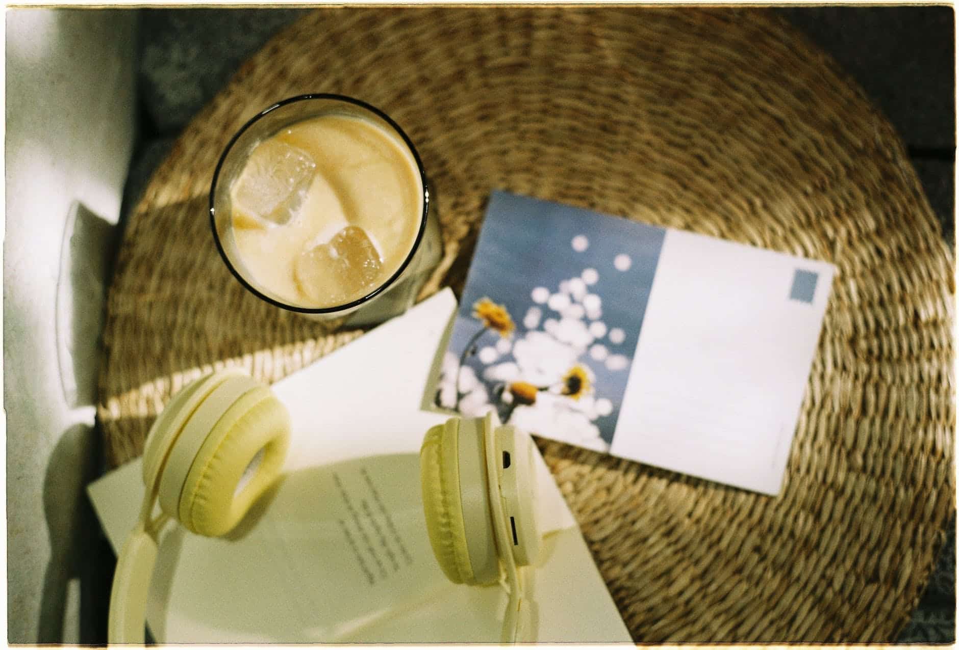 ice coffee headphones and a postcard on a wicker basket